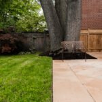 A luxury backyard featuring a mix of artificial turf, stone walkways, and custom garden beds by UBL Group.